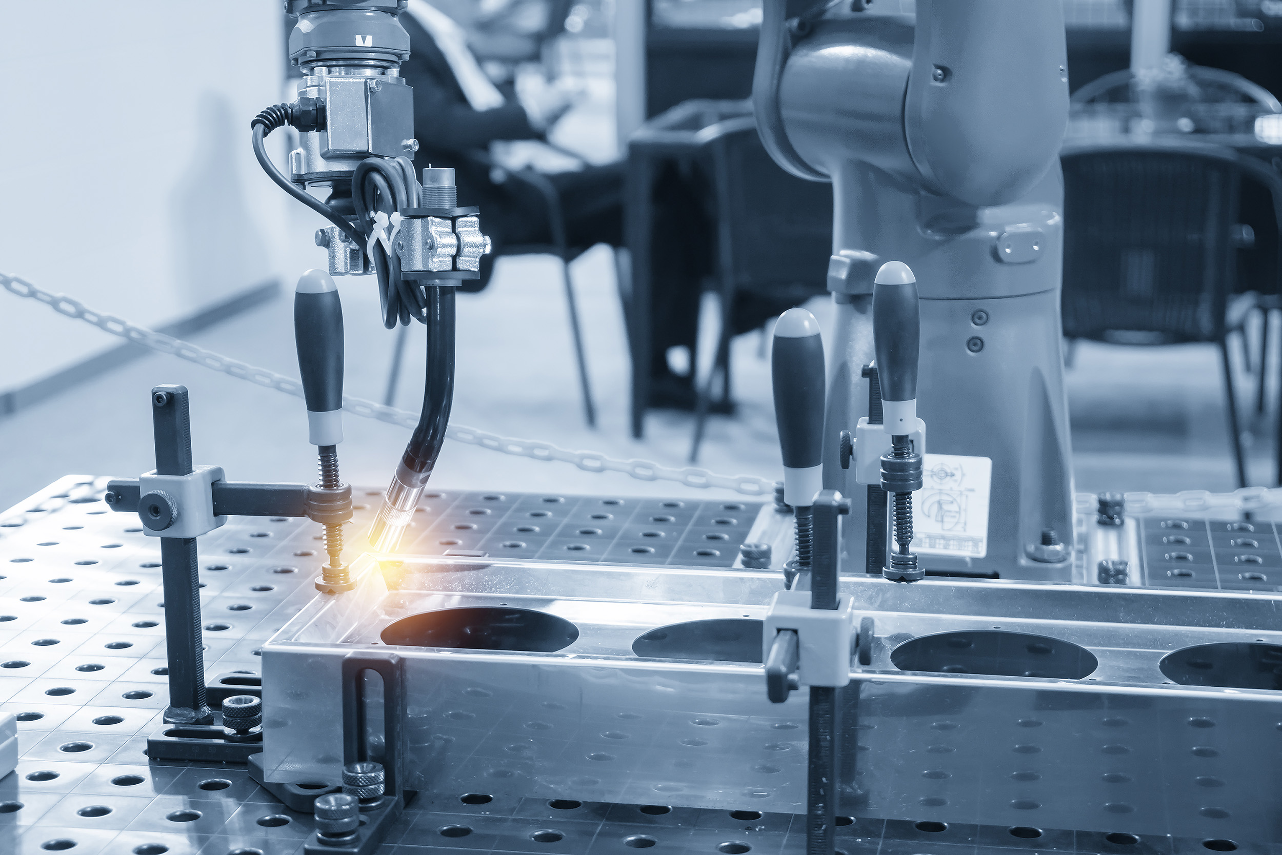 The welding robot machine for welding automotive part in the light blue scene.